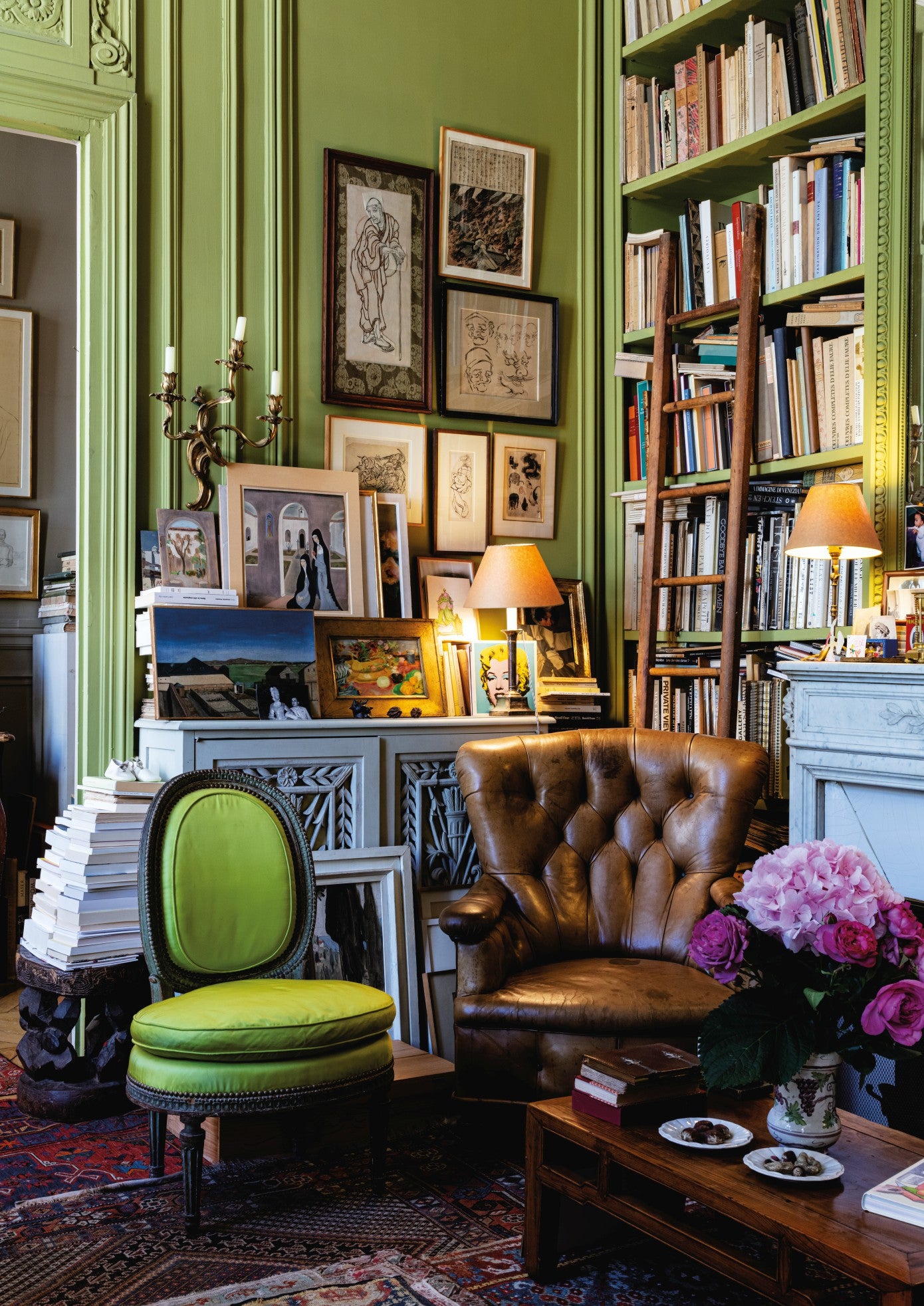 interior design showcasing paintings and bookshelves on green walls